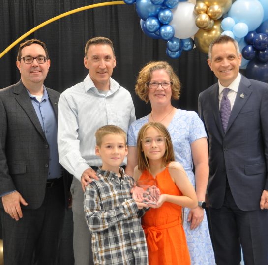 Griffin and Nova Scarborough stand in the front row holding the family's Group of the Year award. In the back row, from left to right are Councillor Glen Gower, Chad Scarborough, Jennifer Rowland and Ottawa Mayor Mark Sutcliffe.